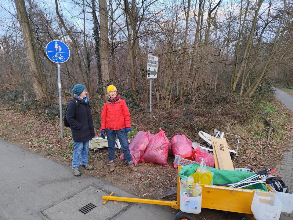 Cleanupcrew steht bei dem abgeladenen Muell, entladener Waste-Buster im Vordergrund